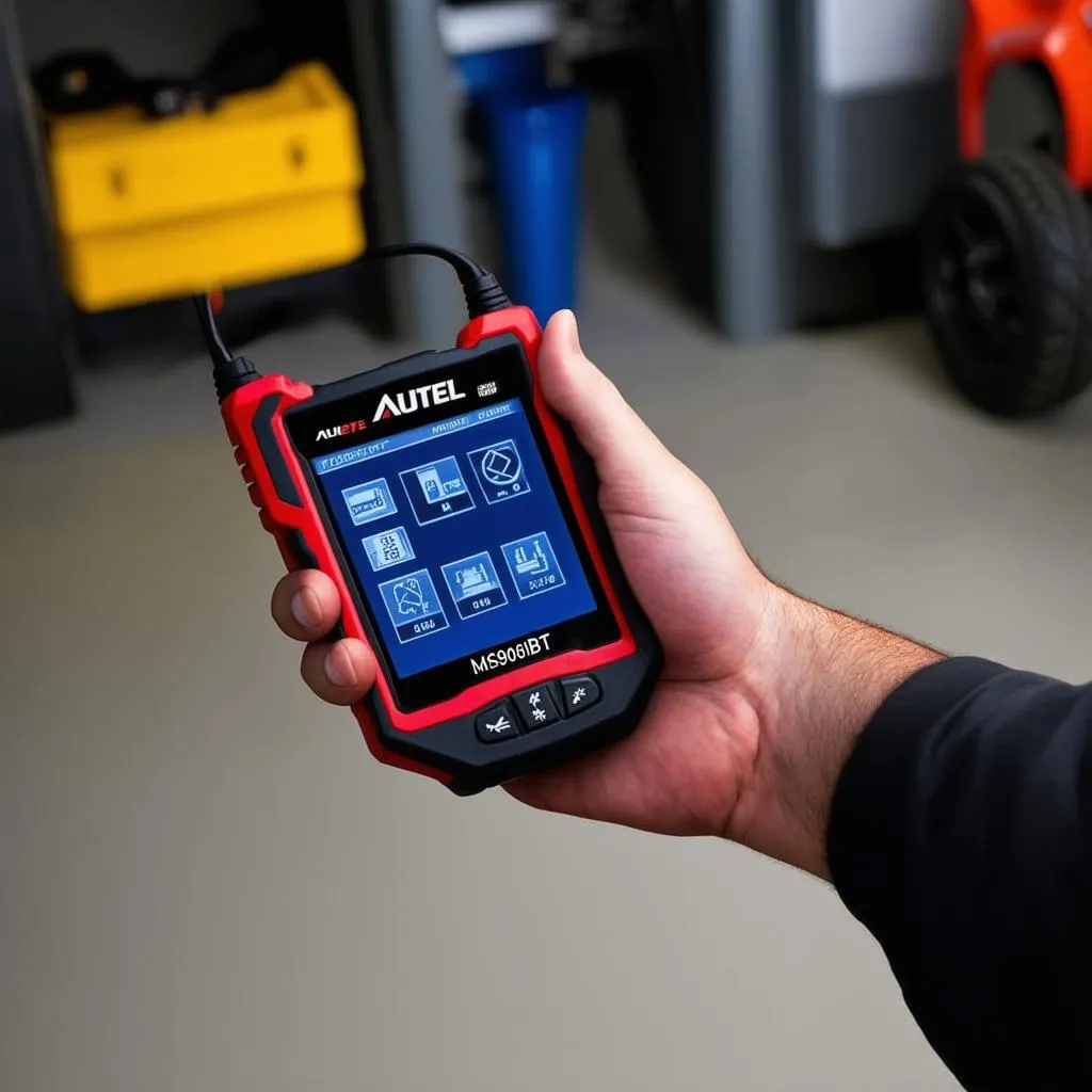 Autel MaxiSys MS906BT diagnostic tool being held in hand.