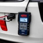 Autel scanner with OBD1 connector plugged into a car