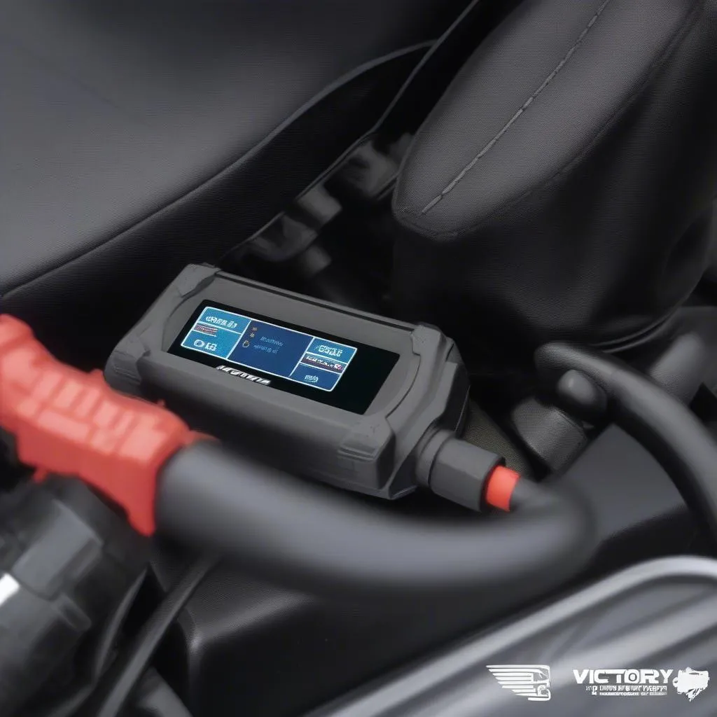 A Victory motorcycle scan tool connected to the OBD-II connector under the seat